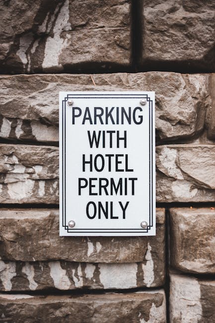 A rectangular white parking sign mounted on a wooden post outdoors, featuring a blue background with a white wheelchair symbol indicating accessible parking, and a separate blue square with a white 'P